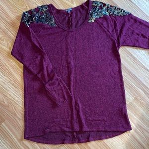 burgundy sweater with gold and black details on sleeve